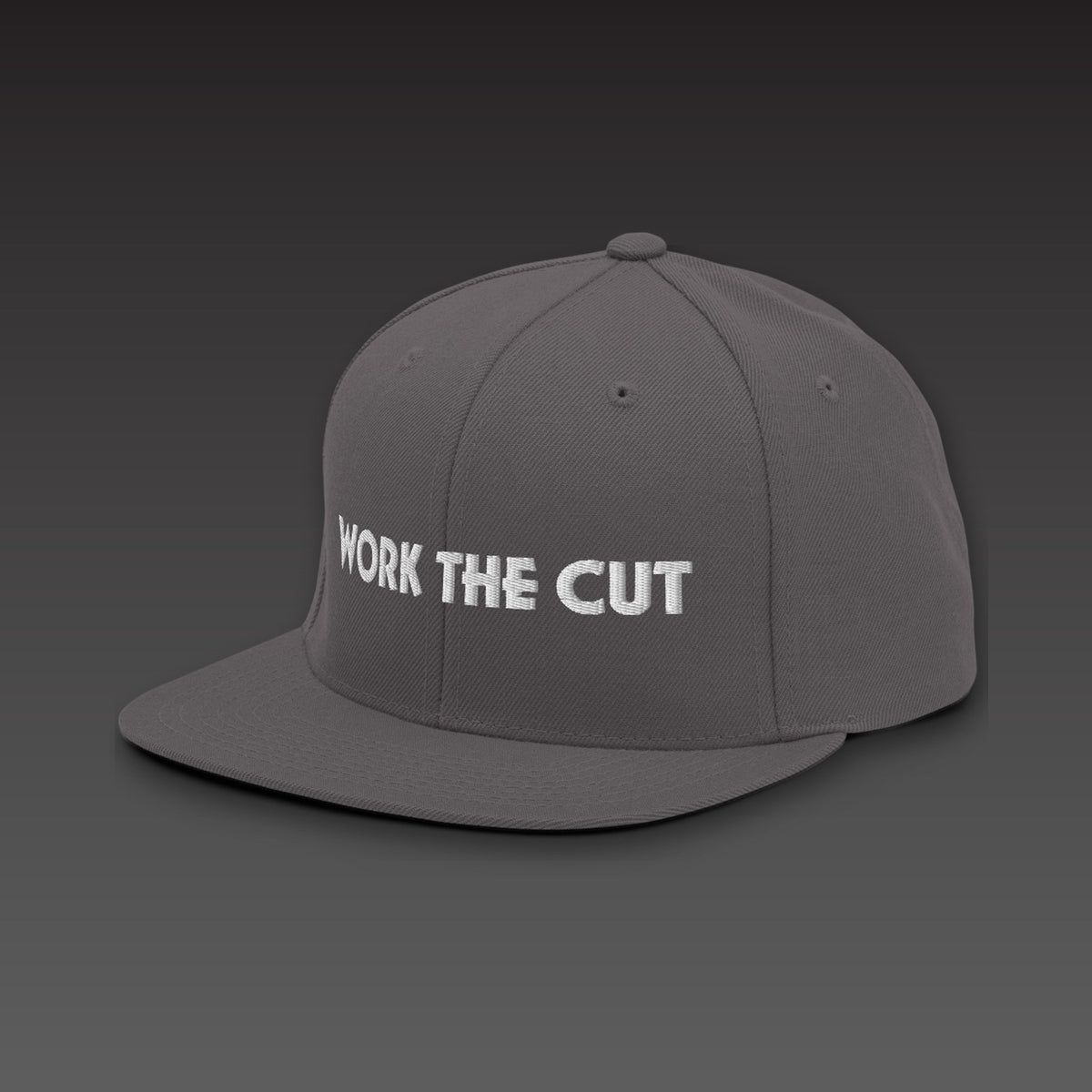 One-Line Flat Bill in dark grey / white, WORK THE CUT in one line of white embroidery across the front, seen from the side